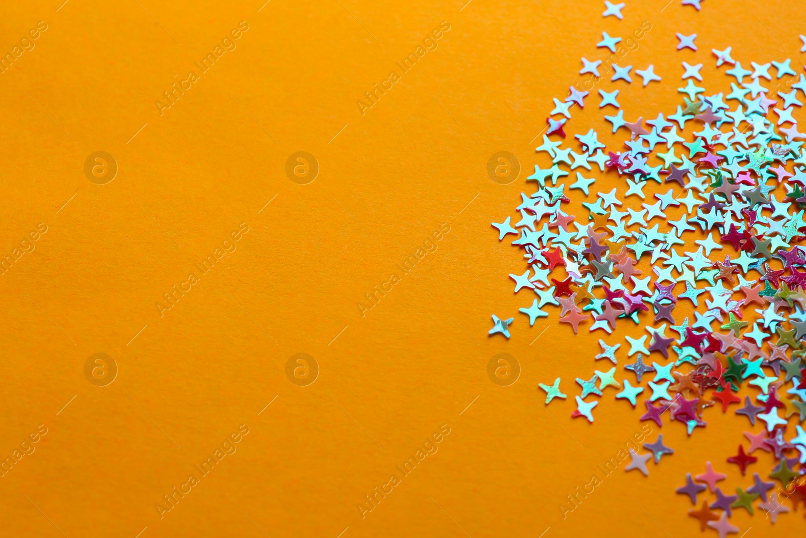 Photo of Shiny bright colorful glitter on pale orange background. Space for text