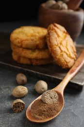 Nutmeg powder, seeds and cookies on grey table