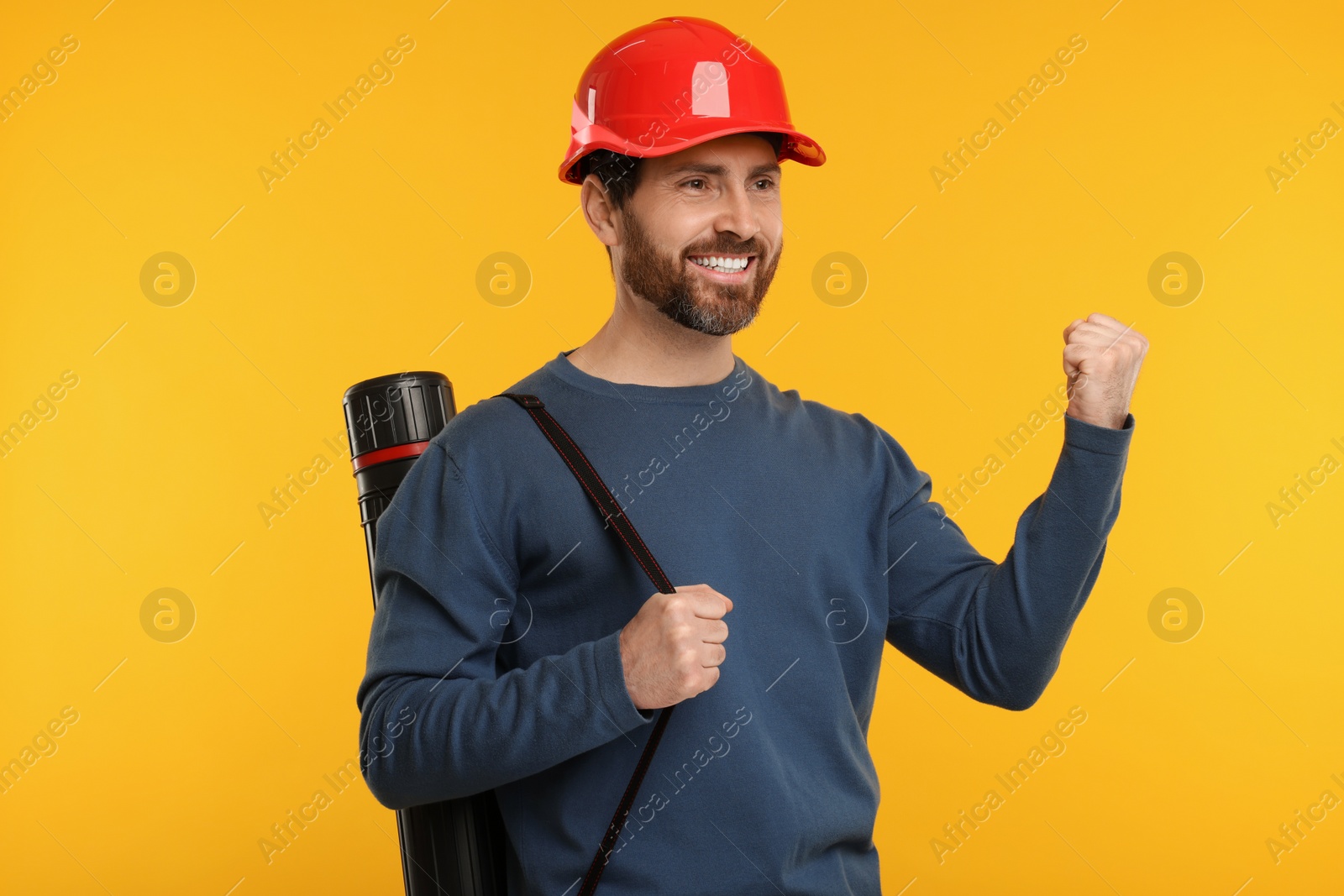 Photo of Architect in hard hat with drawing tube on orange background