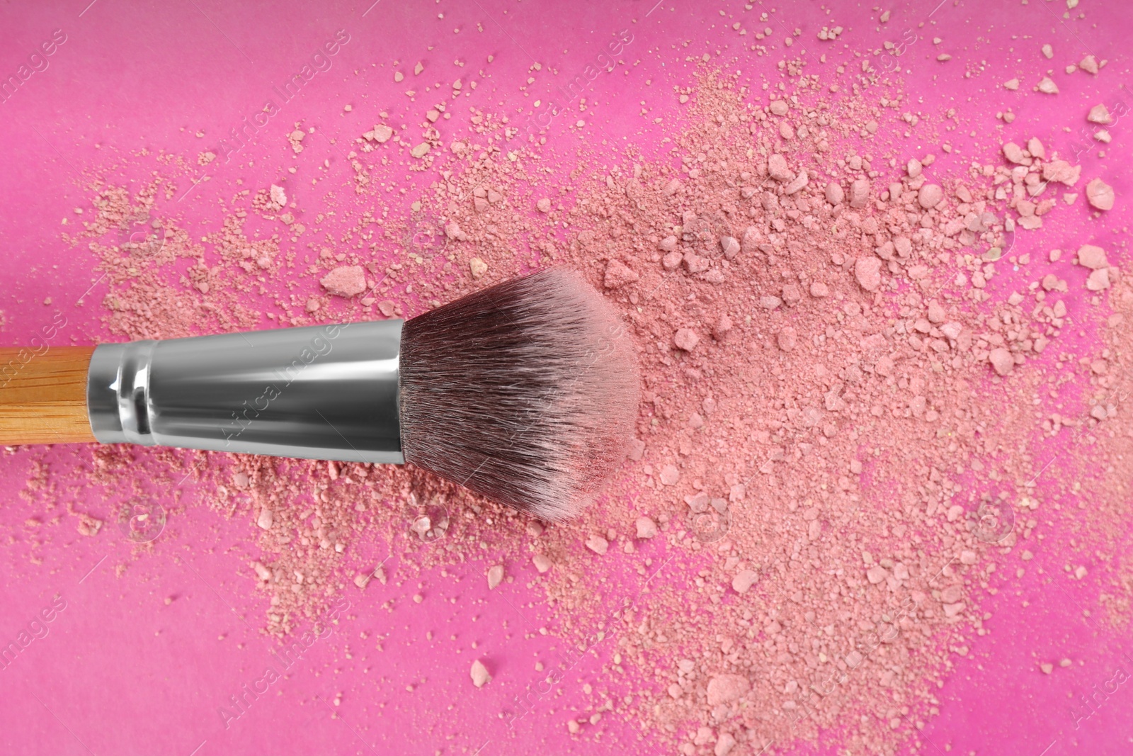 Photo of Makeup brush and scattered blush on bright pink background, top view