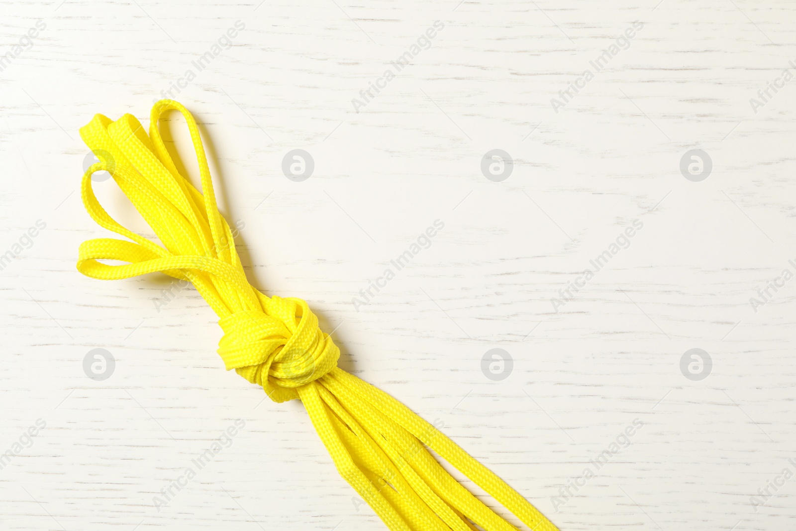 Photo of Yellow shoelaces on white wooden background, top view. Space for text