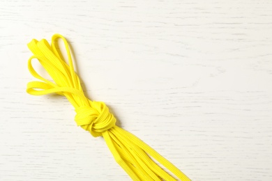 Photo of Yellow shoelaces on white wooden background, top view. Space for text