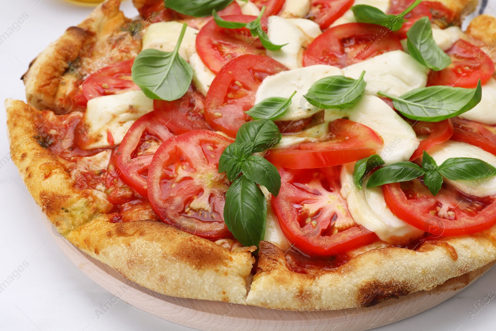 Photo of Delicious Caprese pizza with tomatoes, mozzarella and basil on white table, closeup