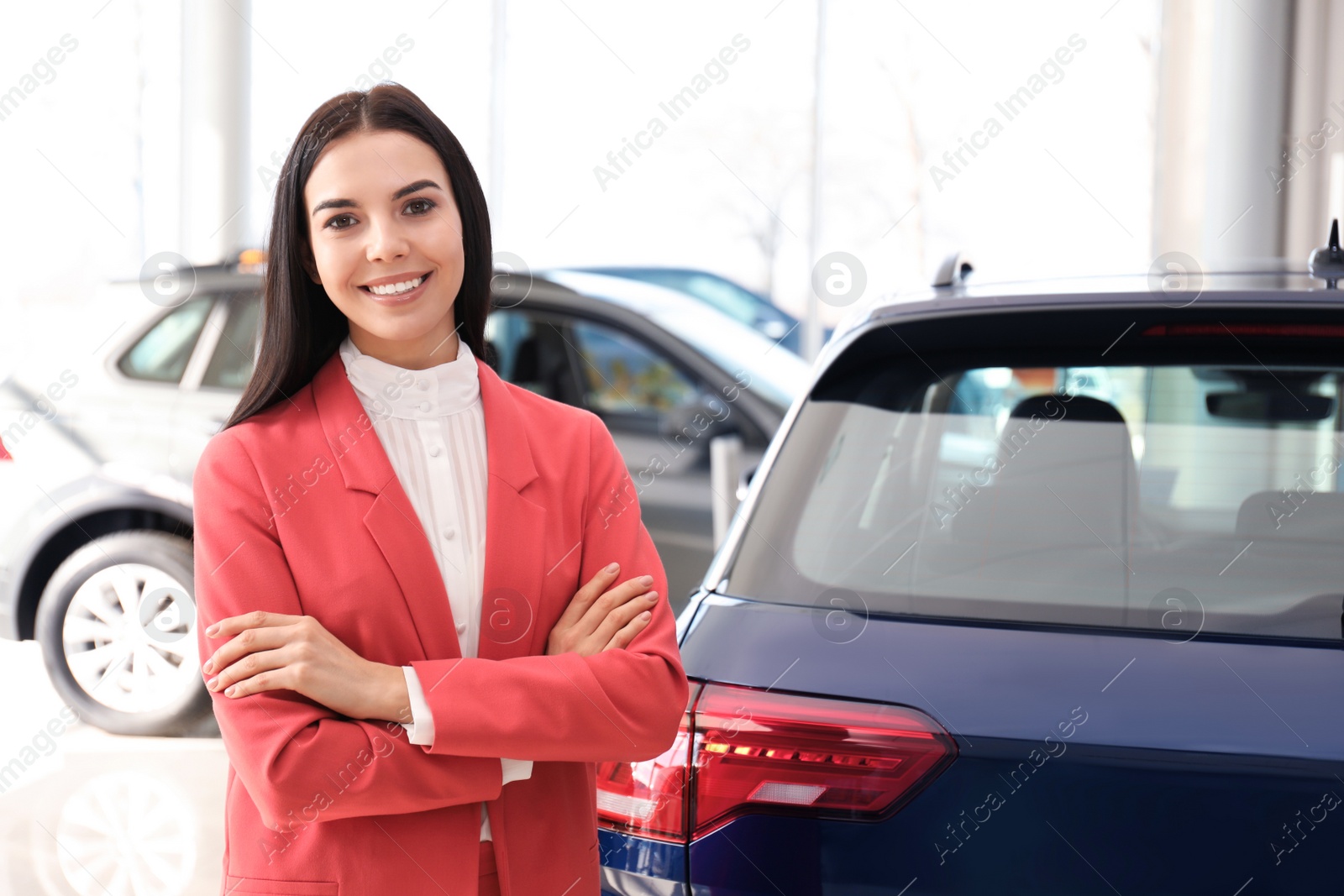 Photo of Happy young saleswoman in modern car salon