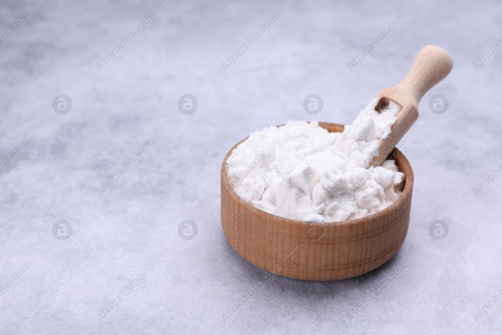 Photo of Scoop and bowl of starch on light gray table, closeup. Space for text