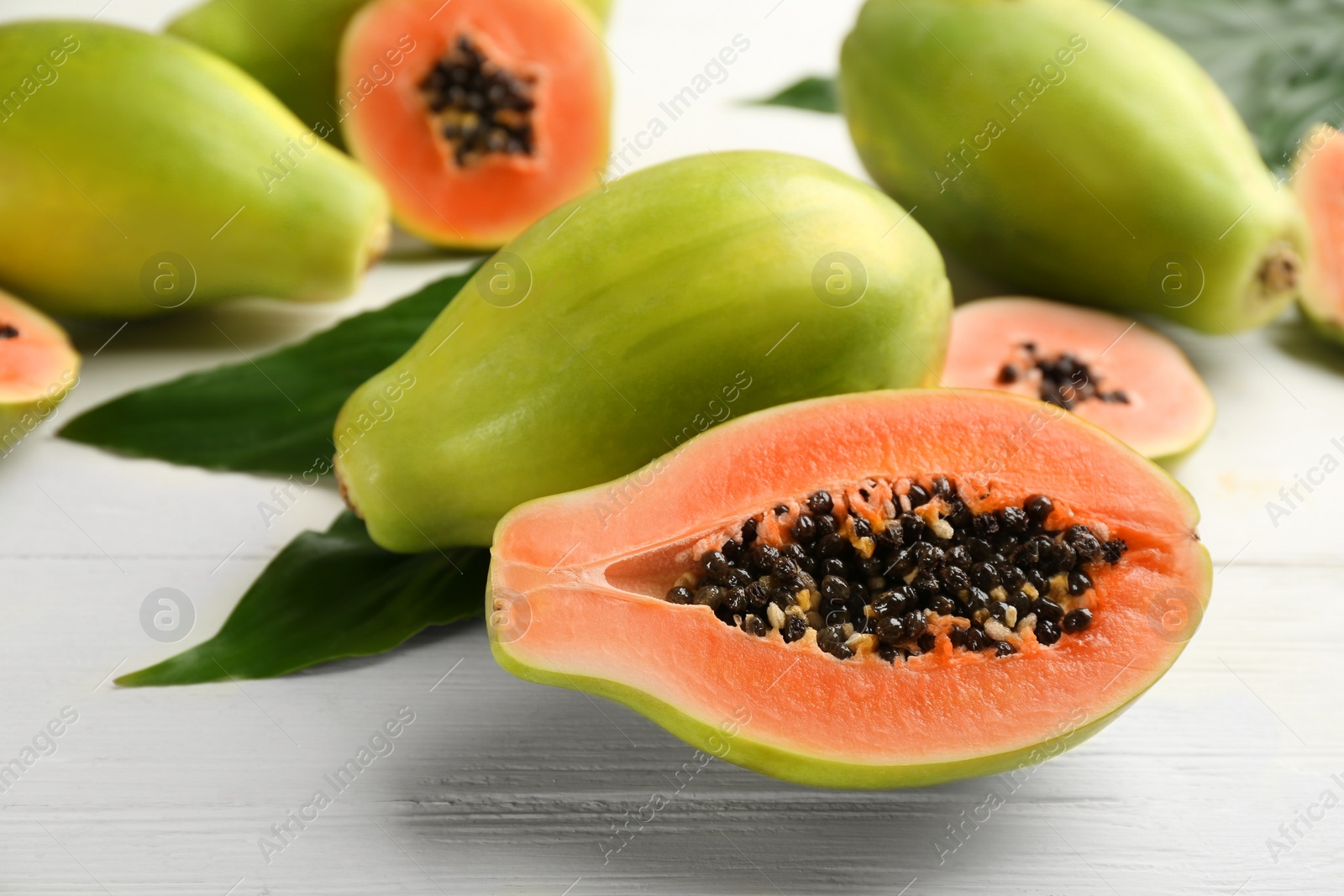 Photo of Fresh ripe papaya fruits on white wooden table
