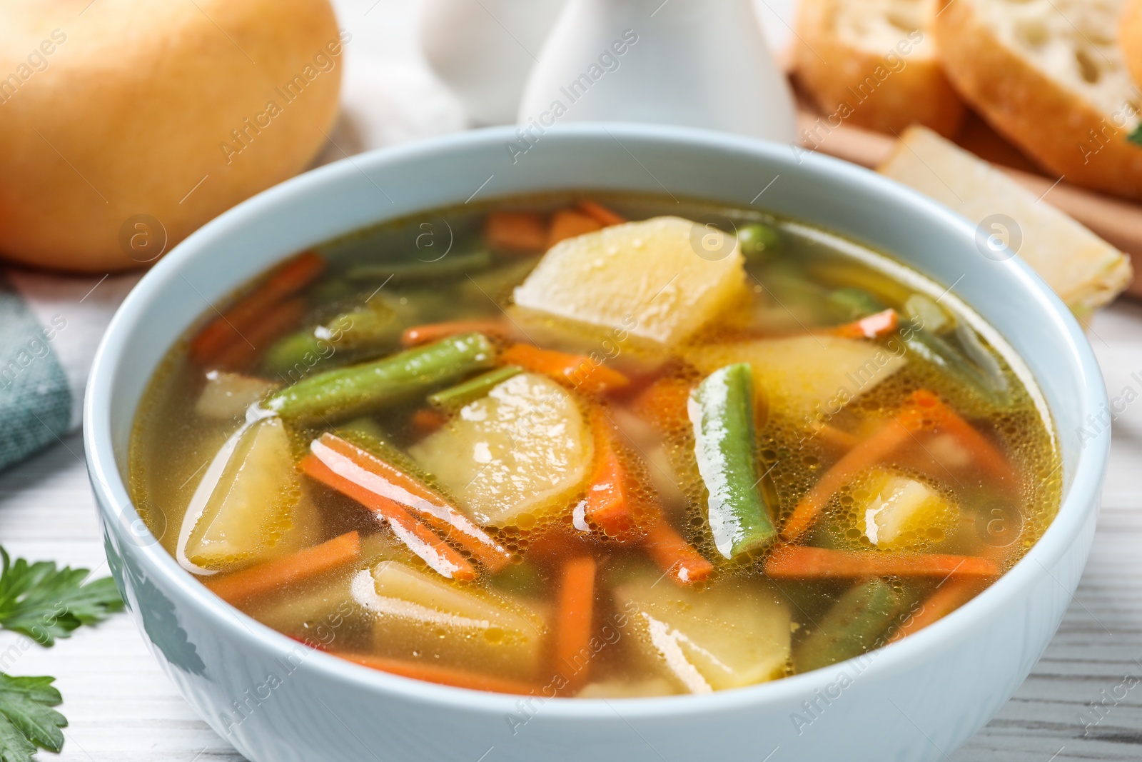 Photo of Bowl of tasty turnip soup on white wooden table, closeup