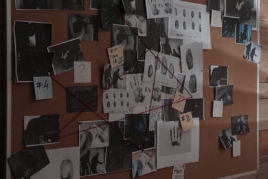 Photo of Detective board with crime scene photos, fingerprints, clues and red thread on wall