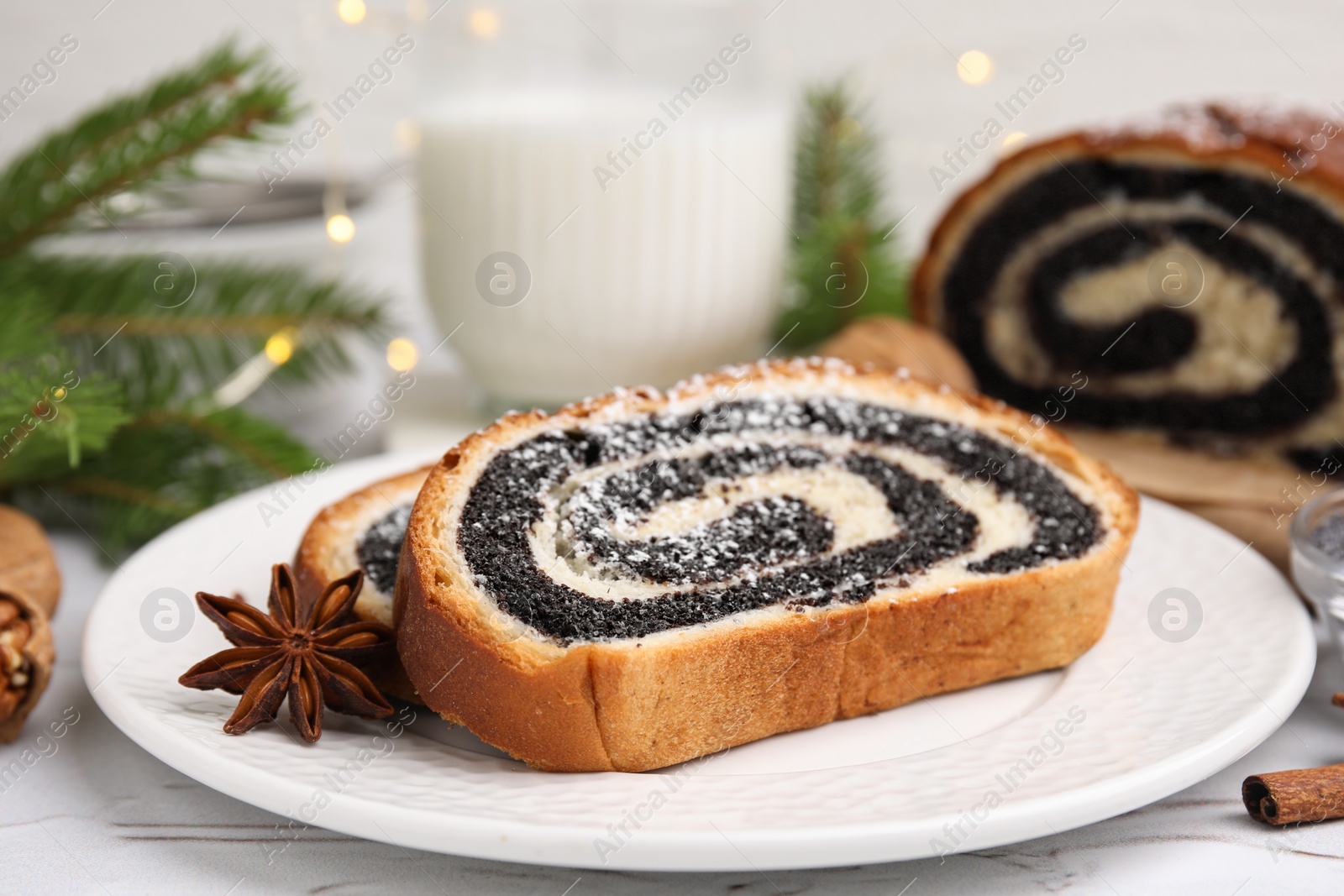 Photo of Slices of poppy seed roll and anise star on white table, closeup with space for text. Tasty cake