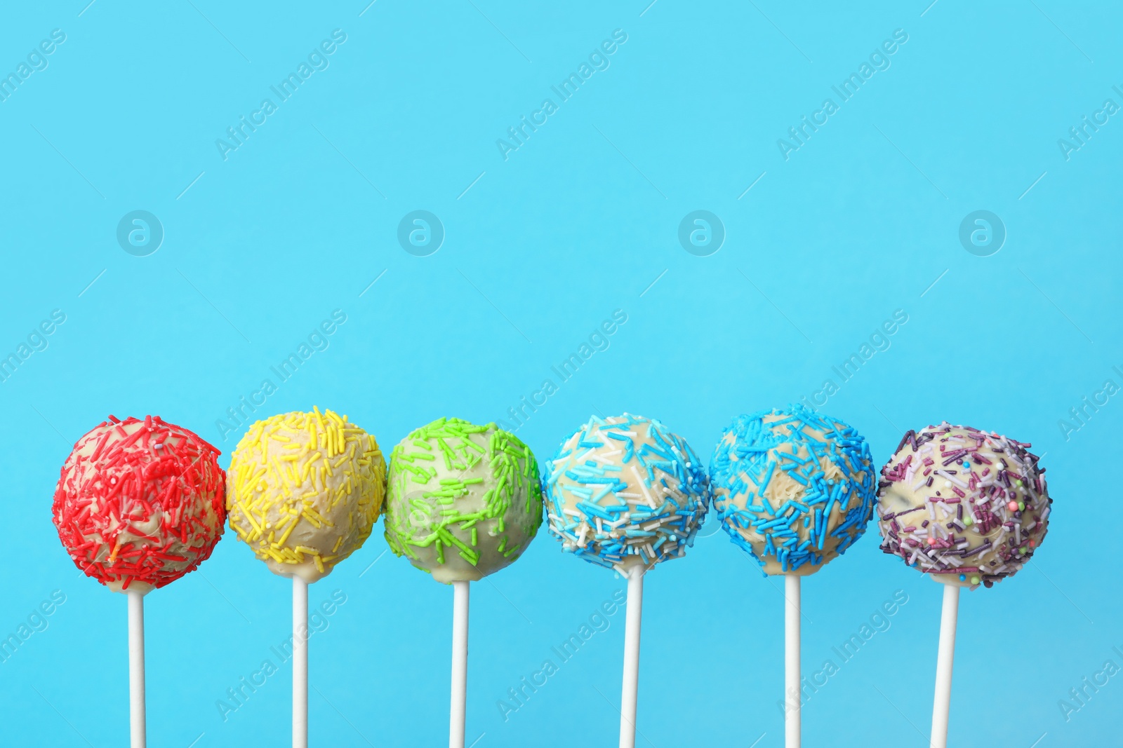 Photo of Yummy bright cake pops on color background. Space for text