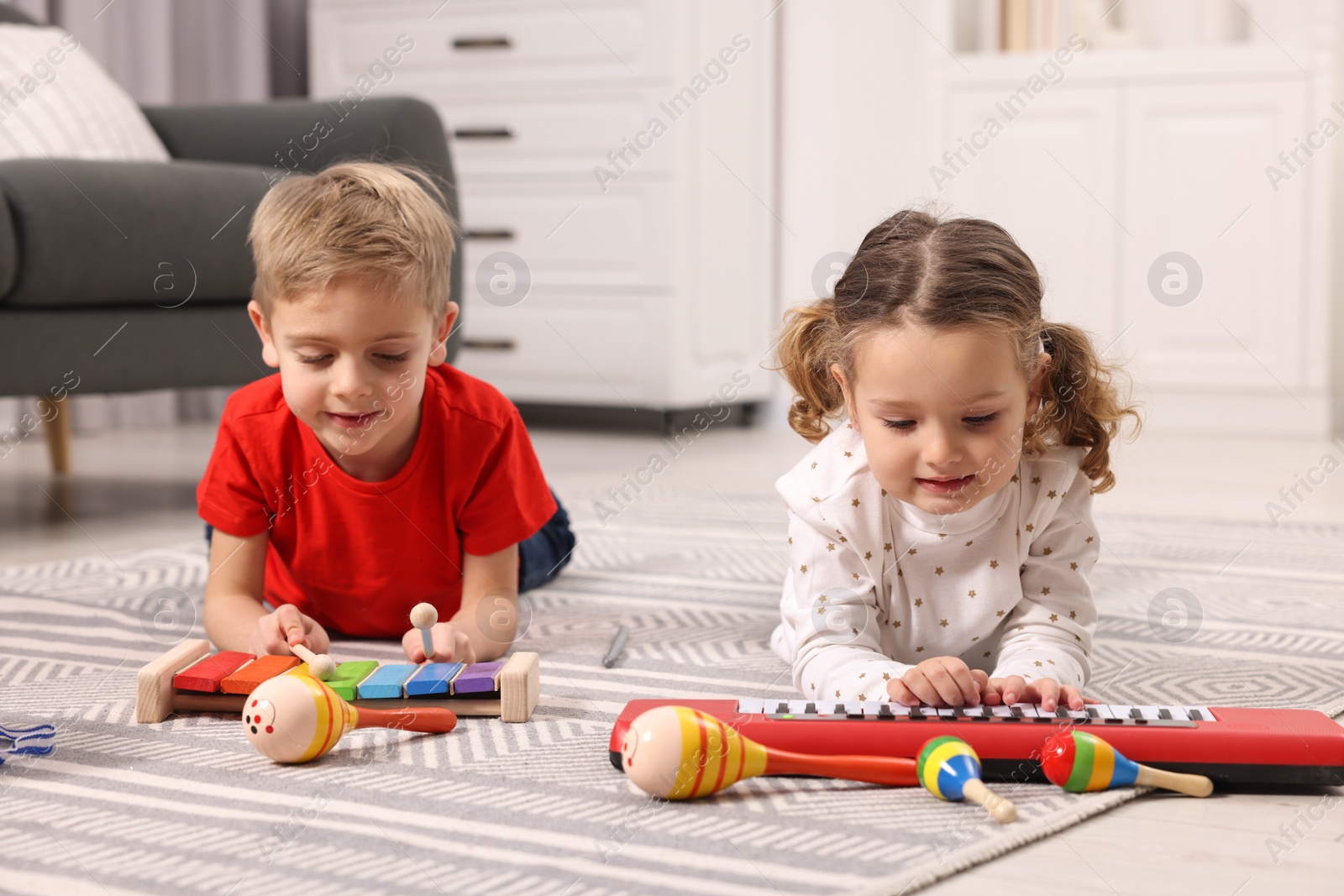 Photo of Little children playing toy musical instruments at home