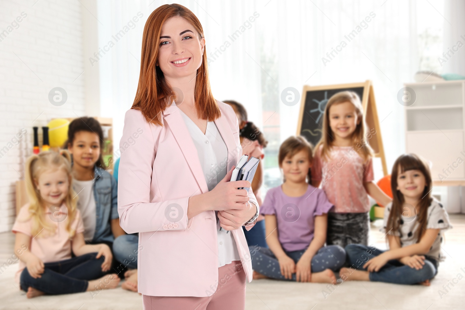 Image of Happy woman in spacious classroom with kids