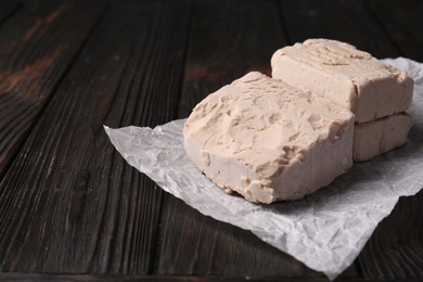 Compressed yeast on wooden table, closeup. Space for text