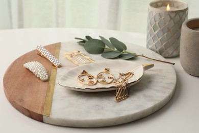 Photo of Stylish golden bijouterie and hair accessories on white table