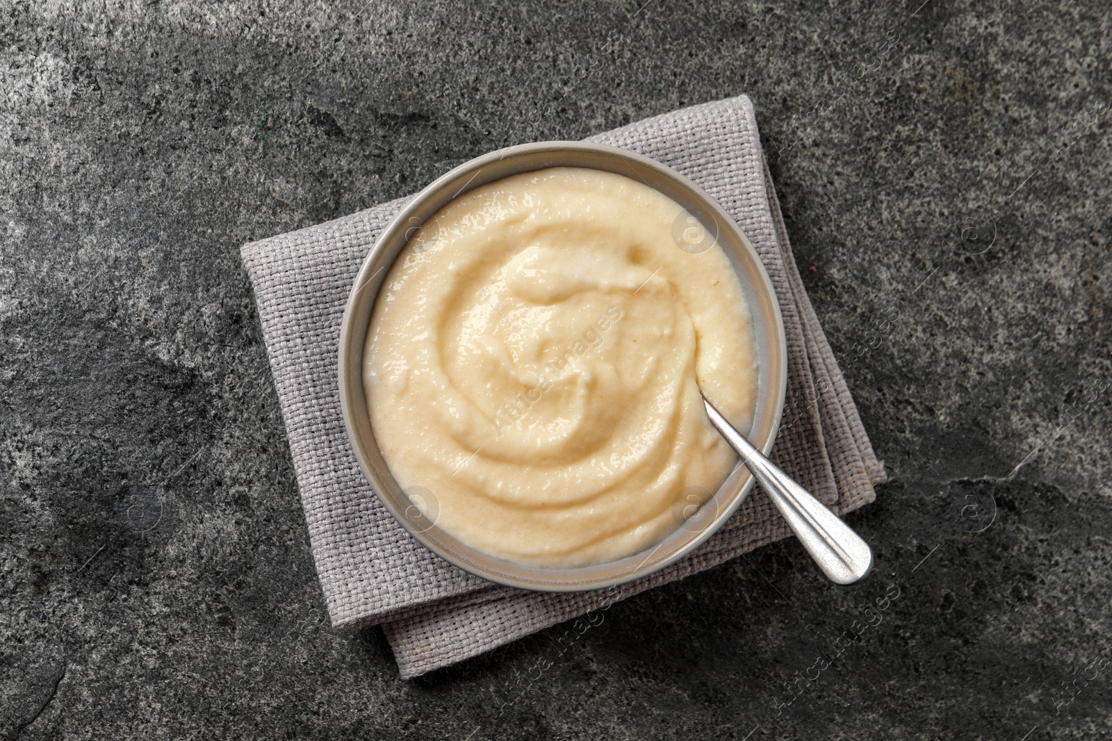 Photo of Bowl with delicious semolina pudding on grey table, top view