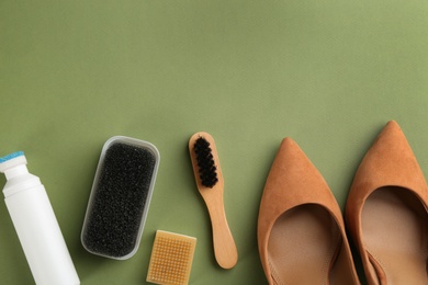 Stylish footwear with shoe care accessories on green background, flat lay. Space for text