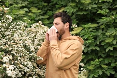 Man suffering from seasonal pollen allergy near blossoming tree on spring day