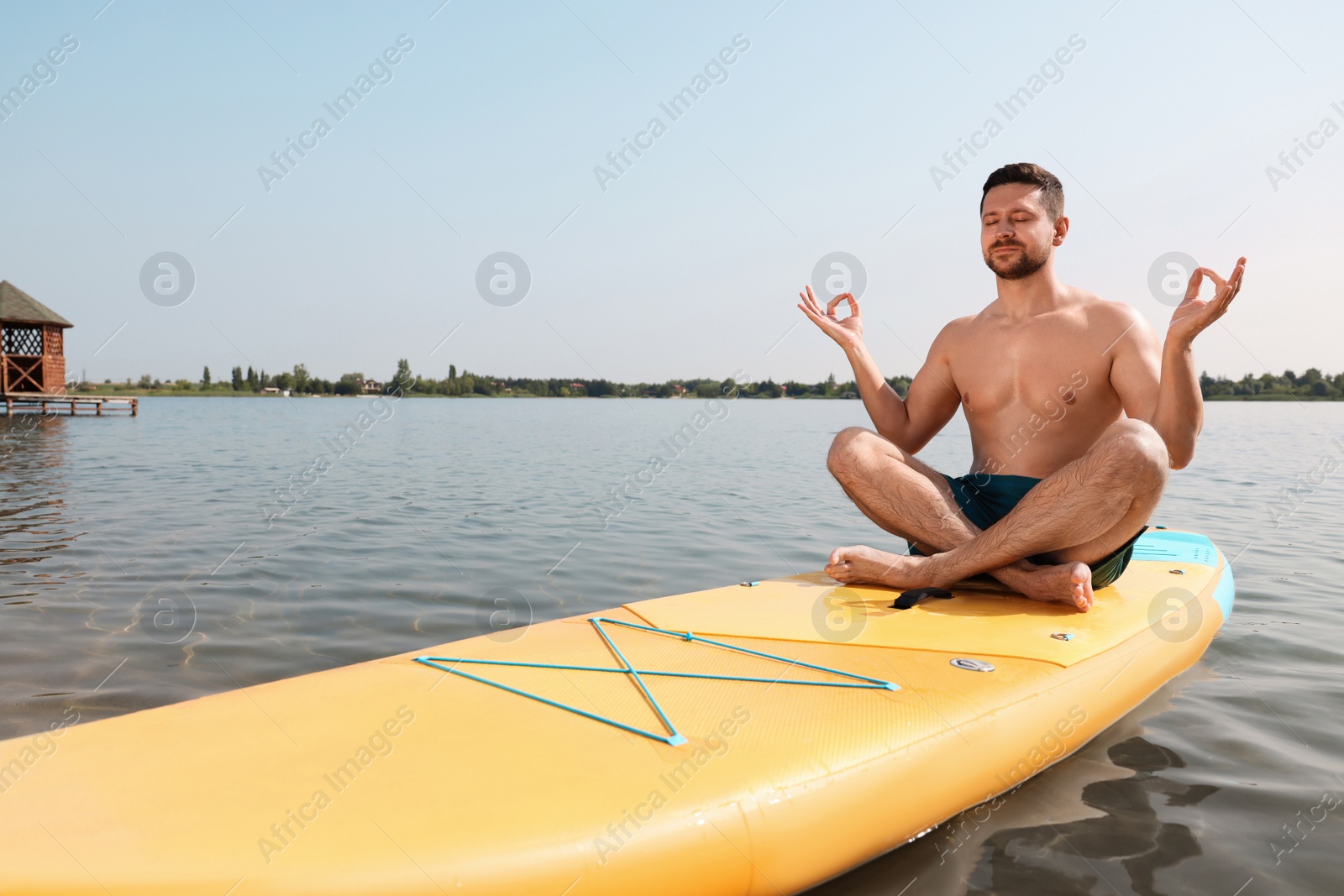 Photo of Man practicing yoga on SUP board on river