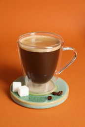Photo of Coaster with cup of coffee on orange background