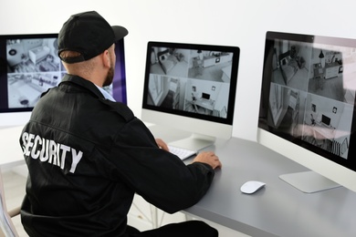 Photo of Male security guard monitoring home cameras indoors