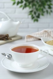 Photo of Aromatic licorice tea in cup and spoon on white table, space for text