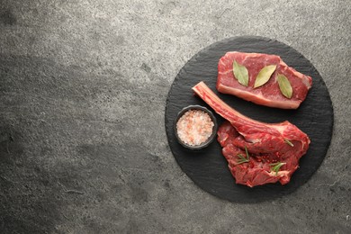 Photo of Pieces of raw beef meat and spices on grey textured table, top view. Space for text