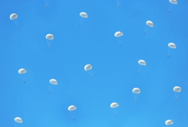 Paratroopers parachuting in blue sky. Military service