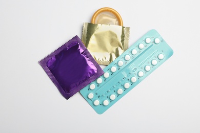 Photo of Condoms and birth control pills on light grey background, flat lay. Safe sex concept