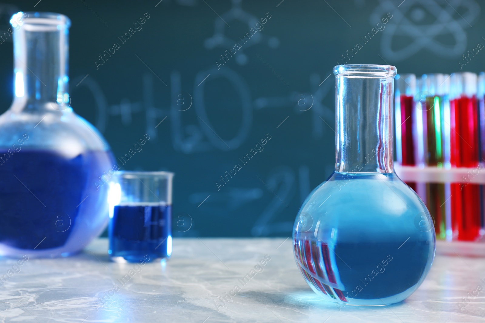 Photo of Round bottomed flask on table against blurred background, space for text. Chemistry glassware