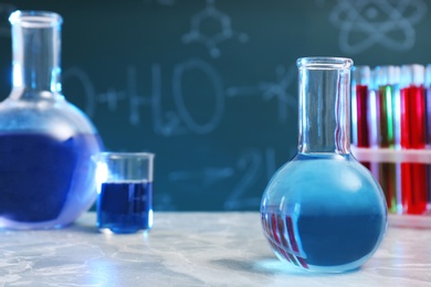 Photo of Round bottomed flask on table against blurred background, space for text. Chemistry glassware