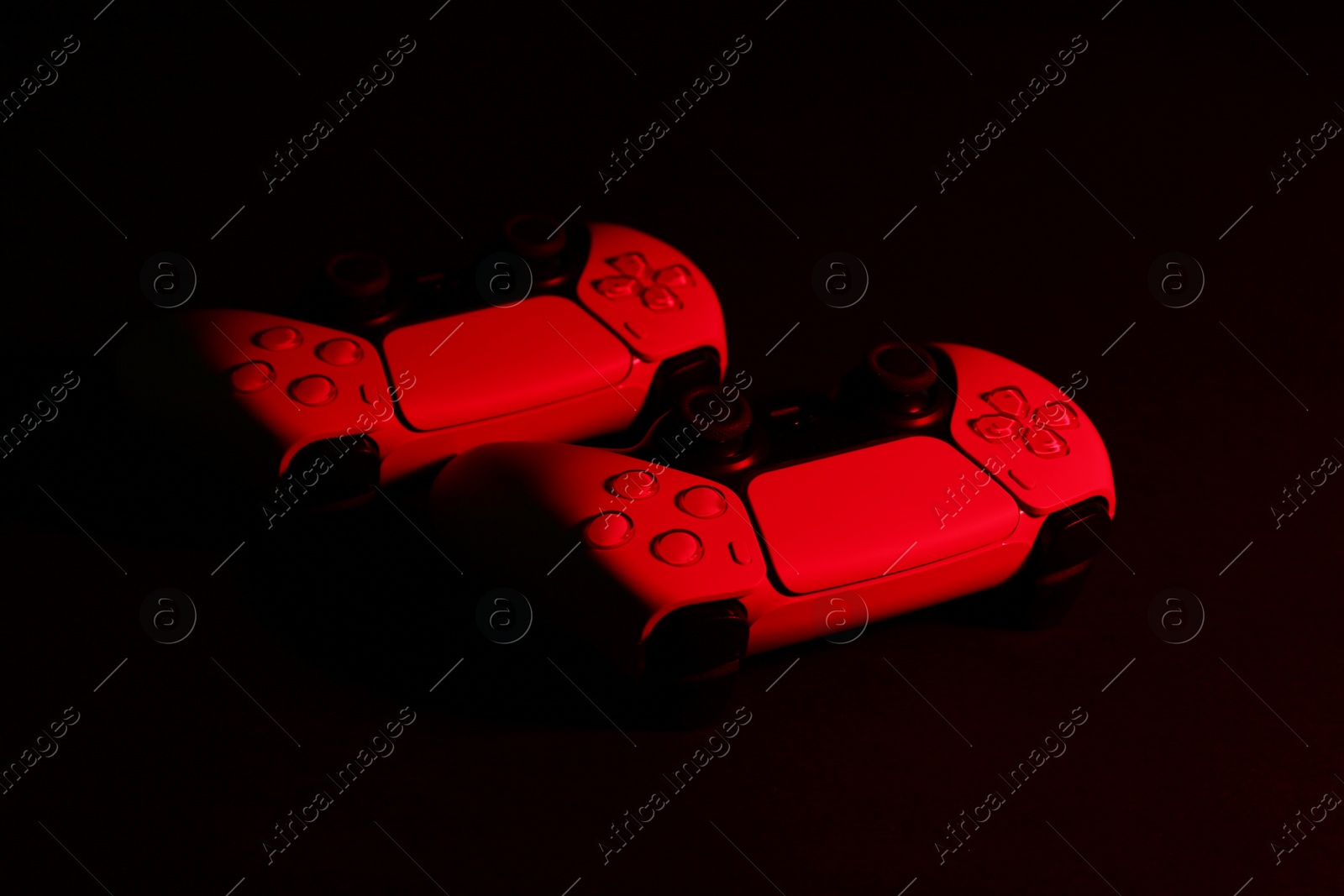 Photo of Two wireless game controllers on black background in neon light