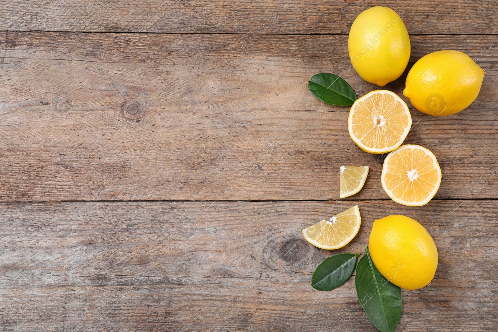 Photo of Fresh lemons and leaves on wooden table, flat lay. Space for text