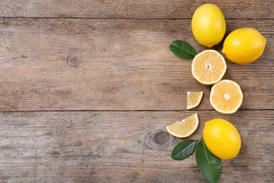 Fresh lemons and leaves on wooden table, flat lay. Space for text