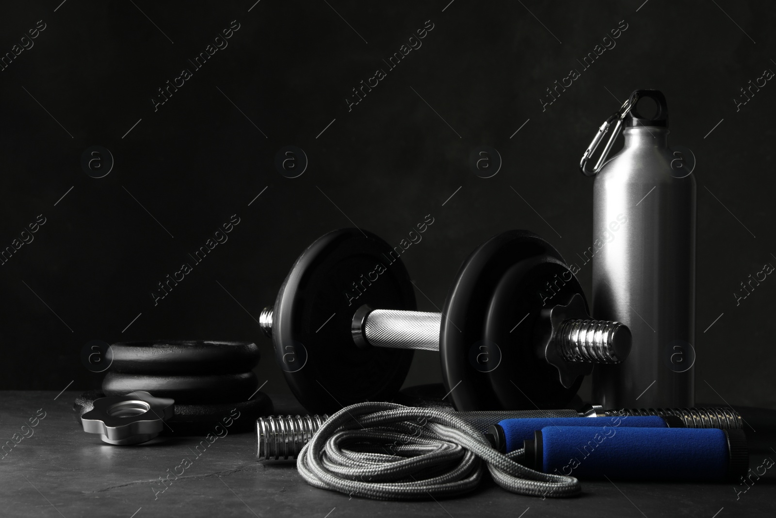 Gym equipment and accessories on stone floor against dark background Photo of Gym equipment and accessories on stone floor against dark background