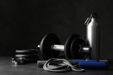 Photo of Gym equipment and accessories on stone floor against dark background