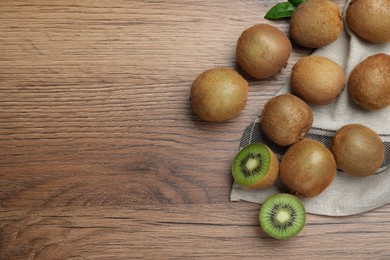 Photo of Fresh ripe kiwis on wooden table, flat lay. Space for text