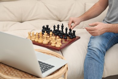 Photo of Man playing chess with partner through online video chat at home, closeup