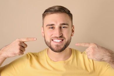 Photo of Young man with healthy teeth on color background