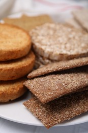 Photo of Rye crispbreads, rice cakes and rusks on plate, closeup
