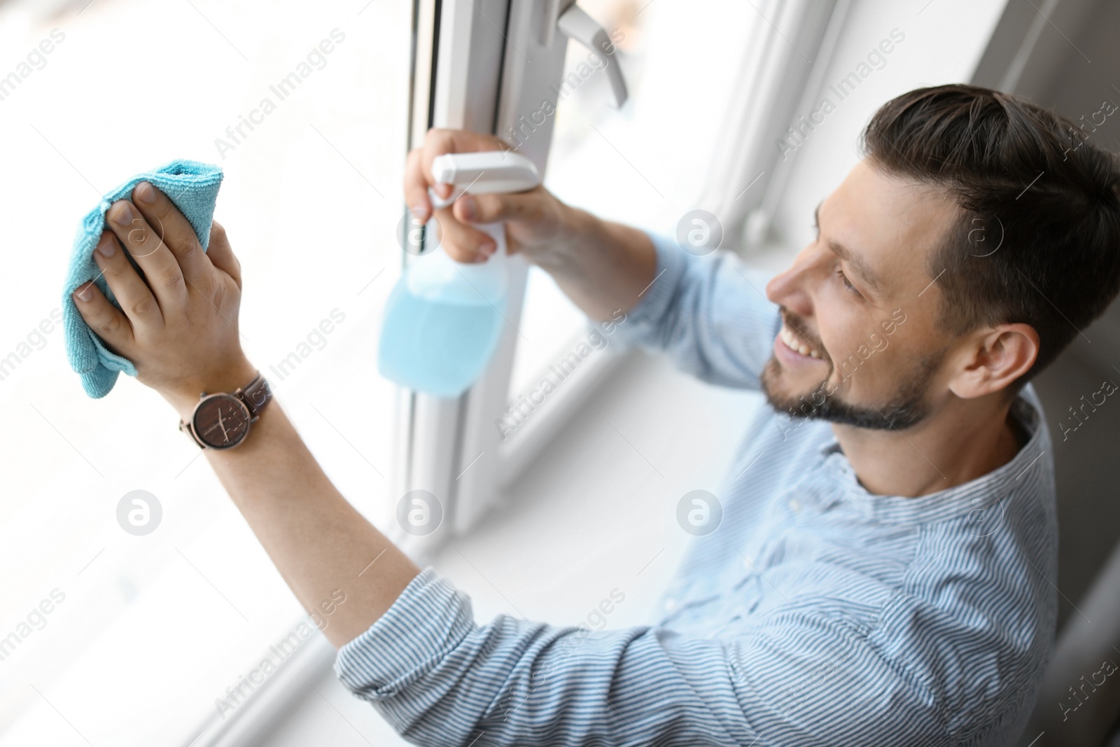 Photo of Man in casual clothes washing window glass at home