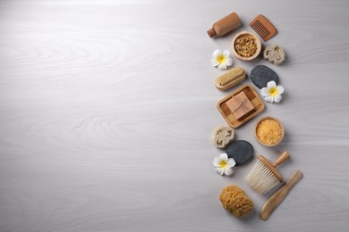 Photo of Flat lay composition with different spa products and flowers on light wooden table. Space for text