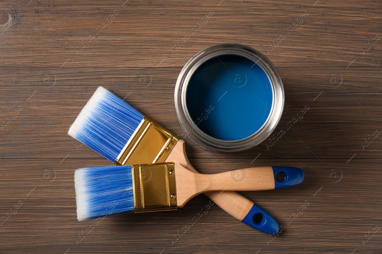 Photo of Can of blue paint and brushes on wooden background, flat lay