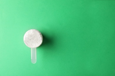 Photo of Scoop of protein powder on green background, top view with space for text