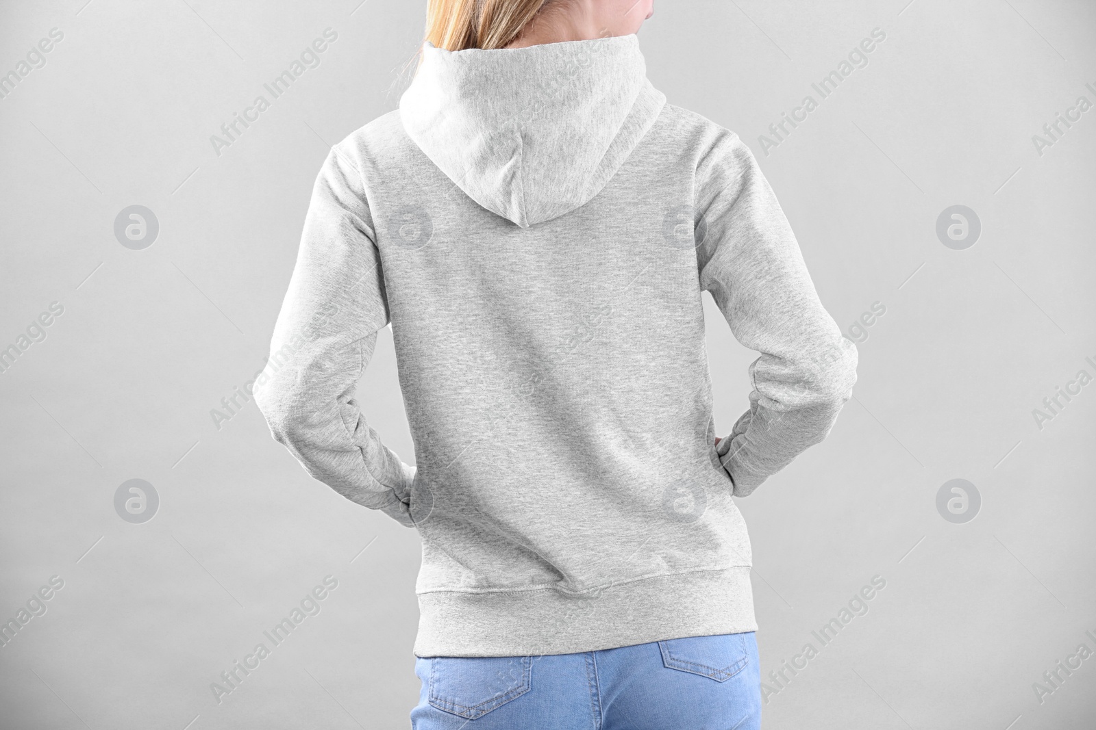 Photo of Woman in hoodie sweater on light background. Space for design