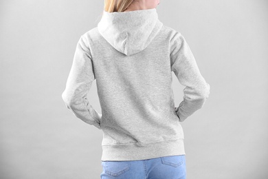 Photo of Woman in hoodie sweater on light background. Space for design