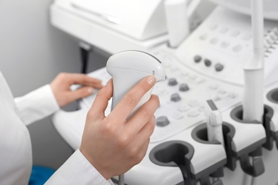 Professional sonographer using modern ultrasound machine in clinic, closeup