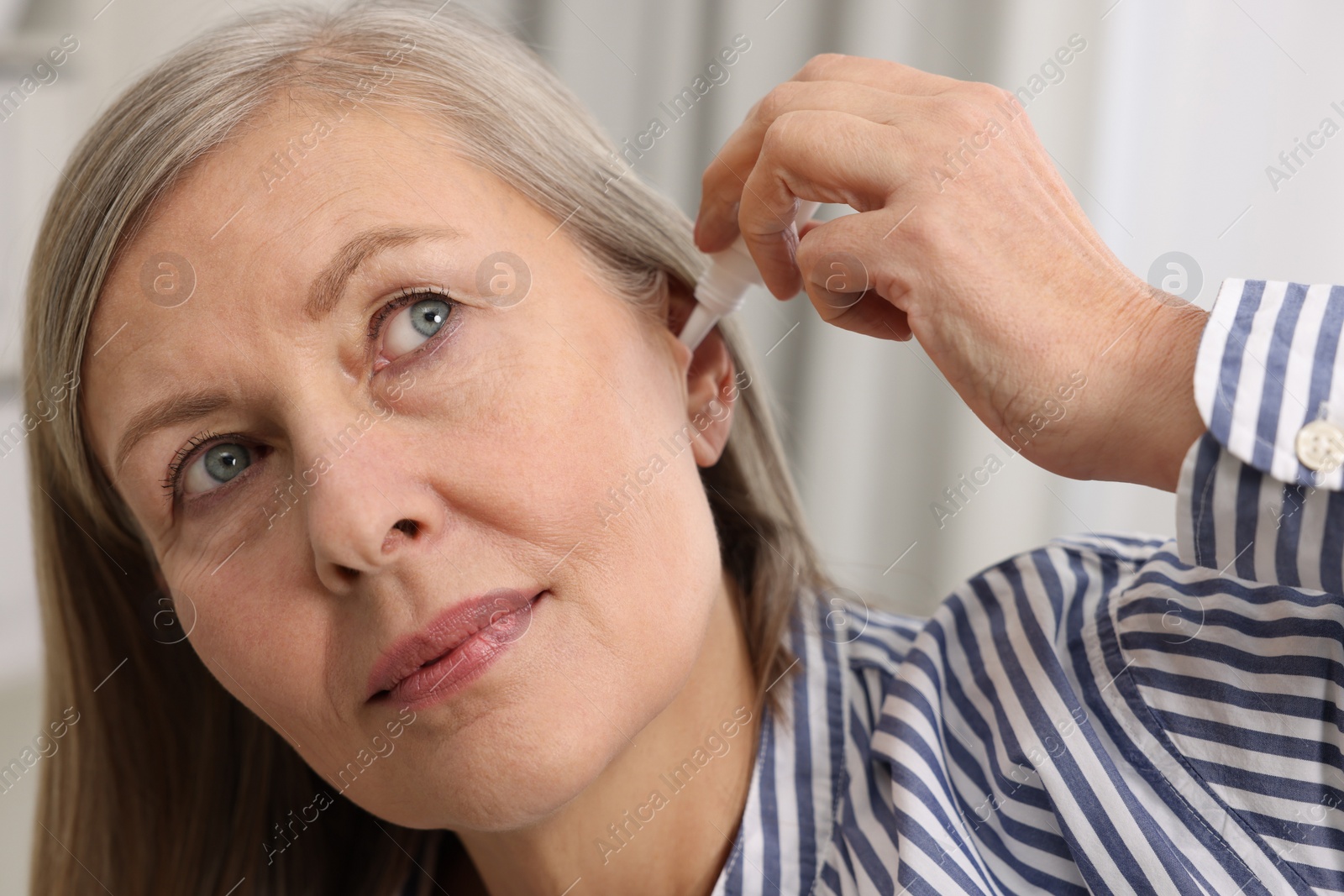 Photo of Woman applying medical ear drops at home