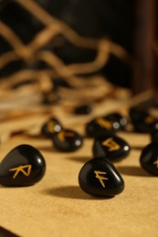 Photo of Many black rune stones on wooden table, closeup