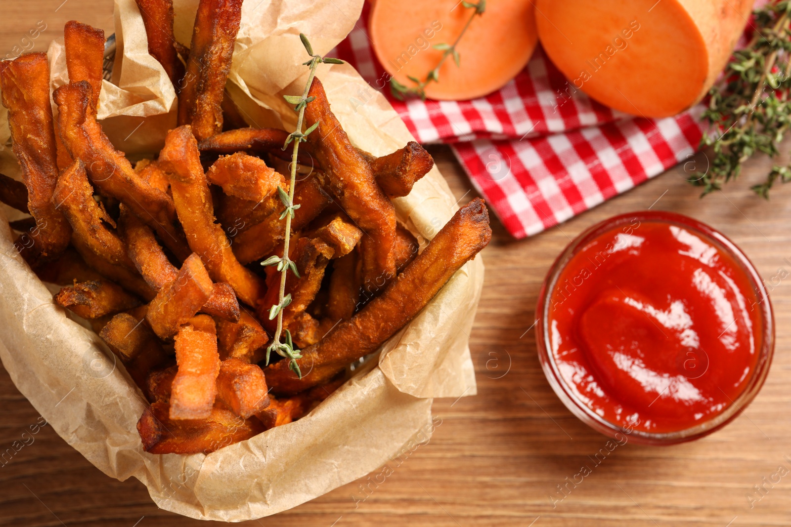 Photo of Sweet potato fries and ketchup on wooden table, flat lay