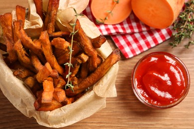 Photo of Sweet potato fries and ketchup on wooden table, flat lay